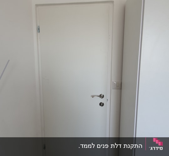 דלת לבנה עם ידית מתכת בחדר קטן